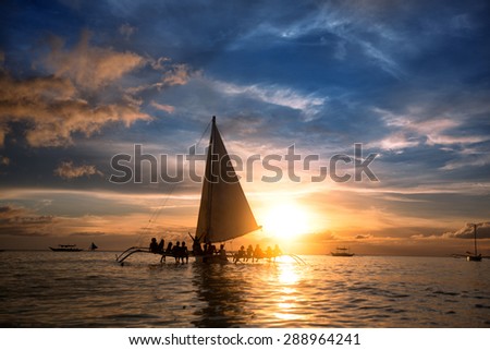 Group of people sitting on sailboat at  ocean and looking  sunset