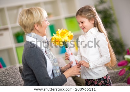 Granddaughter bringing yellow flowers to her grandmother, grandmother day