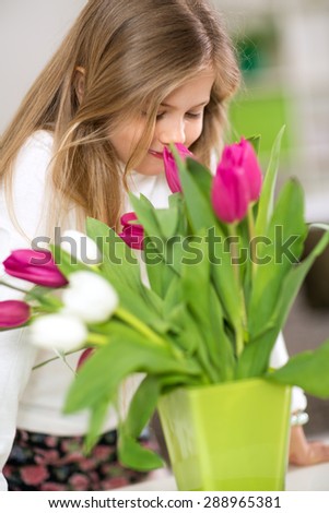 little cute girl smells bouquet of tulips