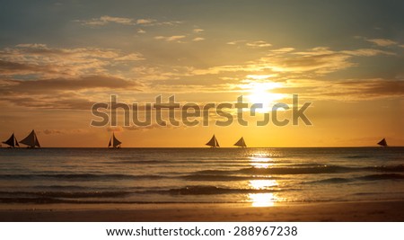 Beach sunset scene with small sailboat