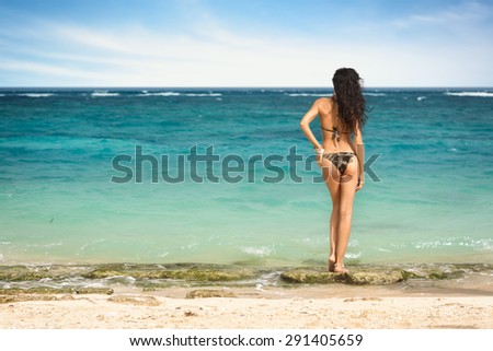 Beautiful sexy young woman in small bikini with standing on the beach