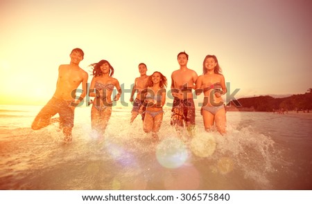 Friends running into the sea, group of happy people having fun