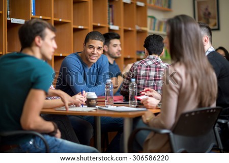Young Latino American student socialize with friends after class in library