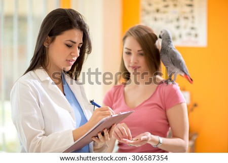 Veterinarian with patient African gray parrot prescribing him a therapy in a vet clinic