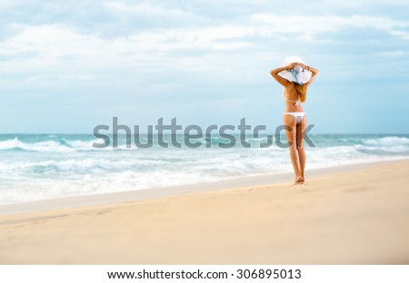 Attractive fit woman standing on  beach, summertime