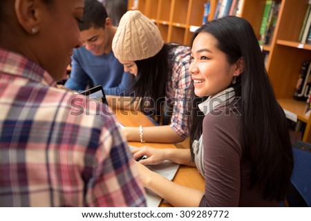 Studding friends socializing and studying together in library