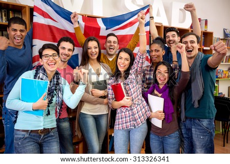 Cheerful British students with raised fists and flag of United Kingdom celebrate victory