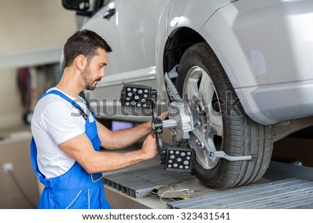 car mechanic installing sensor  adjustment and automobile wheel