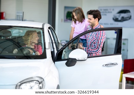 Happy young  family  chooses to buy a car at the car dealership saloon
