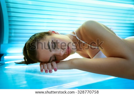 young woman laying on solarium bed and get brown skin tone ready for summer
