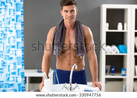Smiling handsome men front mirror with towel on shoulders