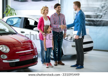 Happy  family buy  new car, car dealer handshaking with daddy congratulated the family on a new car