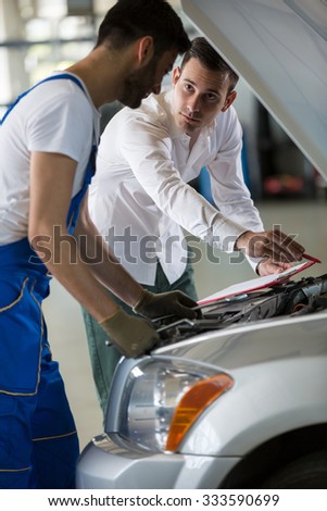 manager and mechanic examine a car damage