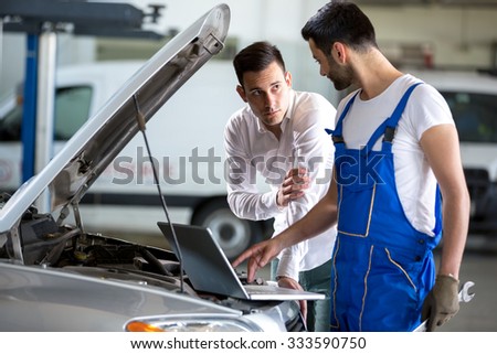 mechanic working on laptop computer with customer