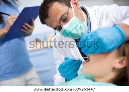 Dentist very  carefully  check up and repair tooth of his young female patient