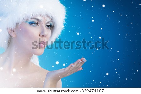 Beautiful snow queen blowing in her open palm