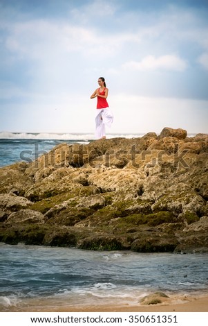 Meditation and yoga , calm woman in zen moment in meditating on rock in sea