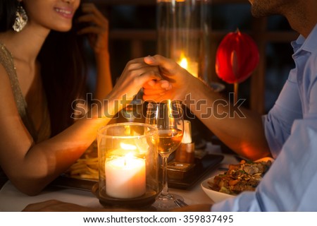 Romantic couple holding hands together over candlelight during romantic dinner