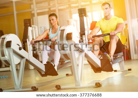 Fit  couple on row machine in gym, sport, fitness, lifestyle, and people concept
