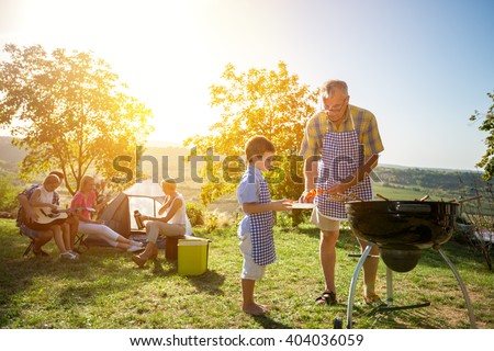 Extended family cooking barbecue in park