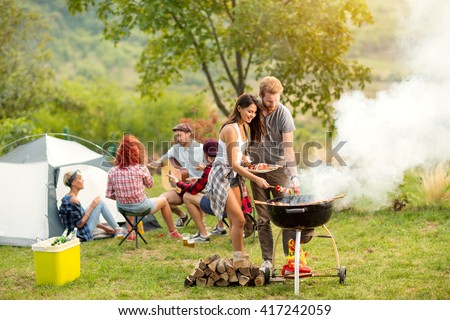 Young female and male couple baking barbecue in nature