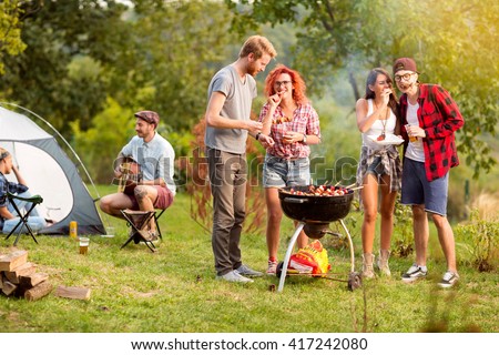 Guys and lassies feed each other with skewers in outing in wood