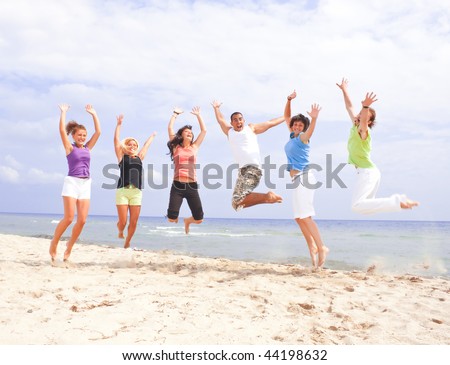 Happy people jumping on the beach by the sea