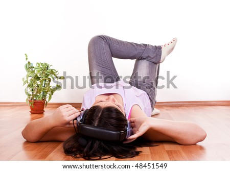 young brunette girl relaxing on the floor with earphones on her head