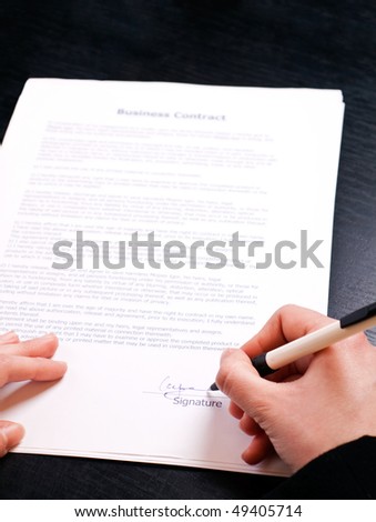 woman\'s hand holding pen and signing papers