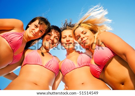 a group of females in bikinis together on the beach looking down