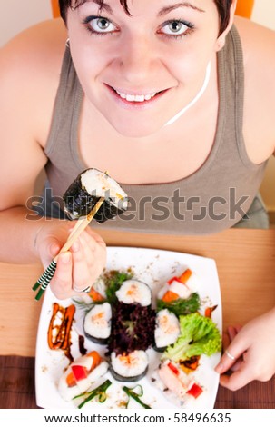 young woman eating sushi roll with chopsticks