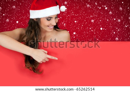 smiling santa girl pointing on red billboard while snowing