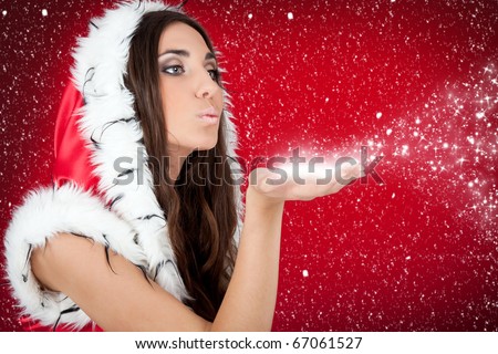 attractive woman in Christmas costume blowing snow form hand