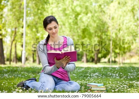 young beautiful woman  on green field and reading book