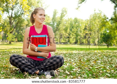 young student girl in park hugging books