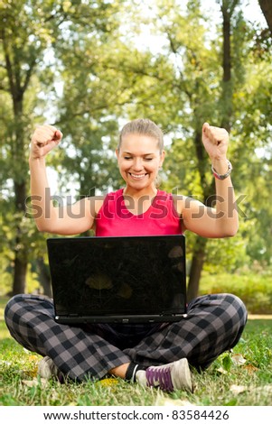 happy winner with laptop in park