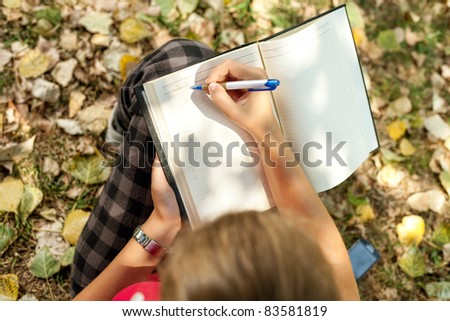 girl sitting outdoor and writing , top view