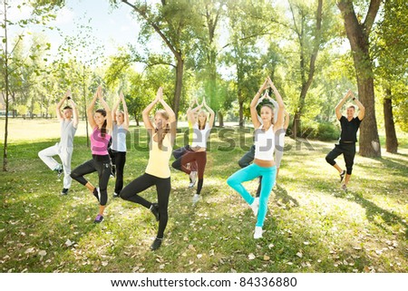 tree position,  large group of young people doing yoga, outdoor