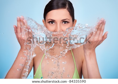 young woman cleaning her face with water