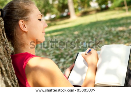 young girl writer in park, writing book