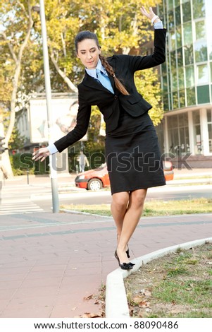 funny businesswoman trying to keep balance on the curb