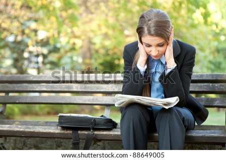 worry businesswoman reading newspaper and holding her head, outdoor