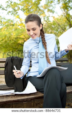beauty businesswoman working with paperwork on bench in park