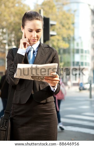 Young business woman in suit reading a newspaper, outdoor