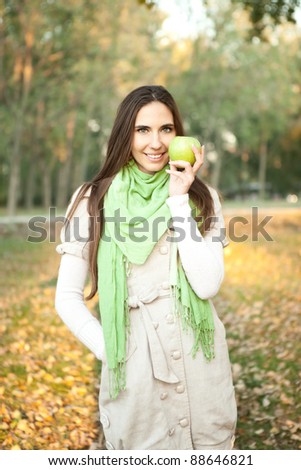 Woman with green apple in autumn park