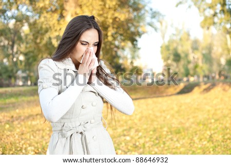 Sick woman with a cold blowing into tissue, outdoor
