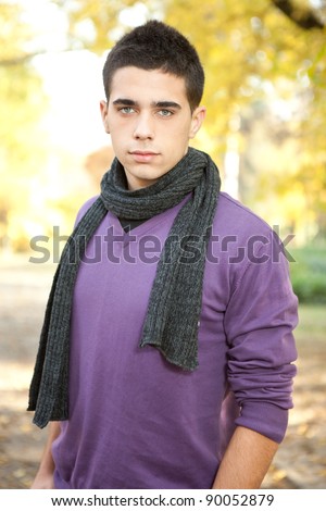 handsome young fashion man posing in autumn park