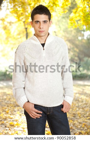 young man in white sweater posing in autumn park