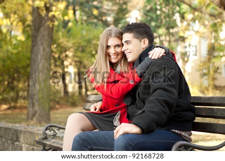 young affectionate couple hugging on bench in park
