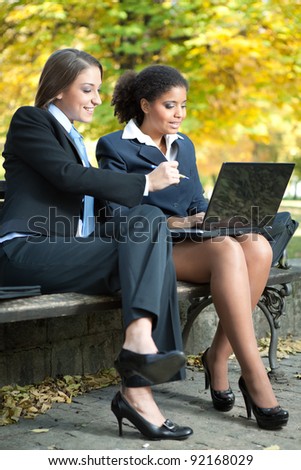 two young businesswoman working on laptop,  outdoor